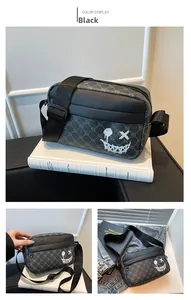 Detail of grey crossbody bag with white devil graffiti and wide nylon shoulder strap