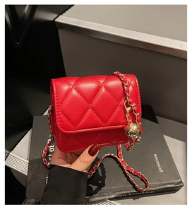 Close-up of red quilted mini bag with gold chain strap and spherical metal charm detail