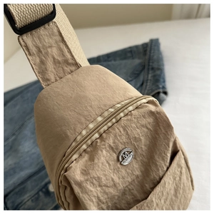 Gros plan du sac de poitrine en nylon beige avec logo M FASHION et tissu texturé