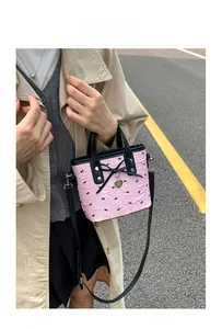 Pink bucket bag with black bows and heart pendant shown in an outdoor lifestyle setting