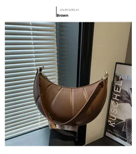 Detail view of brown croissant bag featuring vertical pleats and golden hardware finish