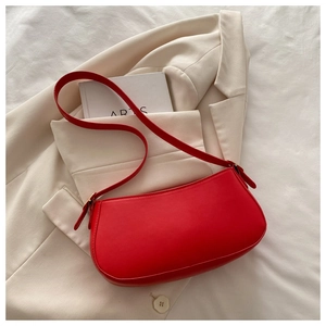 Detail of red crescent shoulder bag with smooth finish on minimalist beige suit jacket