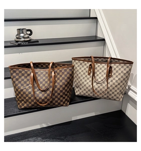 Detail of two large checkerboard tote bags with leather handles in brown and beige