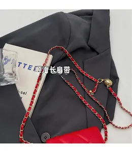 Detail of red quilted leather handbag featuring a golden ball strap adjuster and chain