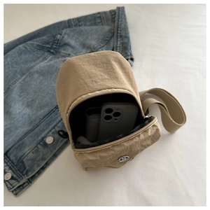 Detailed internal capacity of khaki nylon sling bag showing phone and wallet storage space