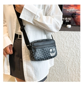 Detail of crossbody bag with grey geometric pattern and white graffiti smiley face