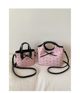 Detail of pink pleated tote bags with black bows and adjustable shoulder straps