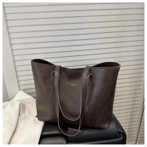 Detailed view of dark brown tote bag with vintage cracked leather texture and gold text