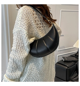 Detail of black pleated croissant shoulder bag with soft padding and golden hardware