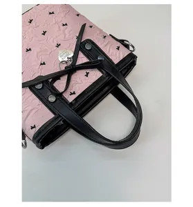 Detail of pink floral tote bag featuring black bow accents and heart metal pendant
