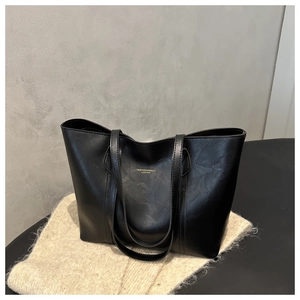 Detail of black tote bag featuring gold embossed lettering on premium textured leather