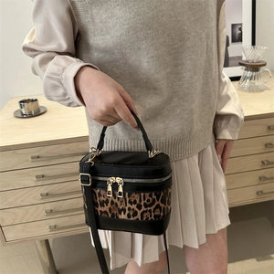 Chic leopard print and black leather cylinder bucket bag shown in a lifestyle scene