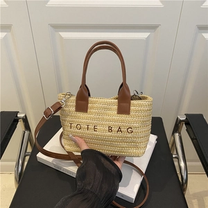 Large woven straw tote bag with brown leather handles and 'TOTE BAG' embroidery for beach use