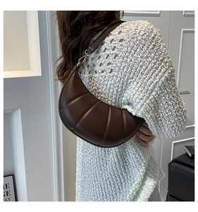 Rear view of model wearing a dark brown quilted crescent shoulder bag in matte leather