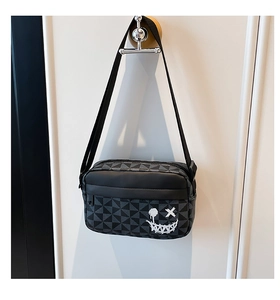 Detail of canvas shoulder bag featuring grey geometric pattern and white graffiti smiley