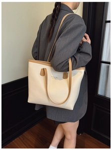 Detalle de bolso tote crema minimalista con asas de cuero marrón y estampado de Nueva York