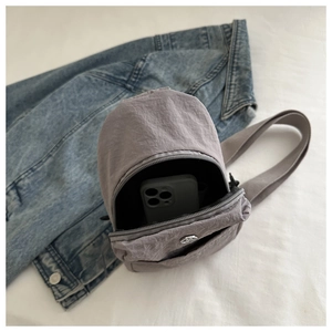 Gros plan sur un sac bandoulière gris en nylon montrant l'espace pour un smartphone