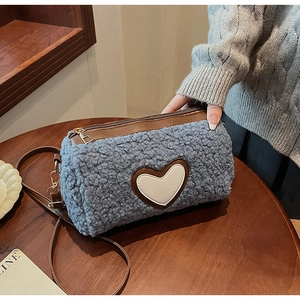 Détail du sac polaire bleu avec écusson cœur en cuir blanc et bandoulière marron