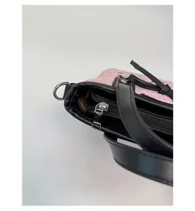 Detail of pink embossed leather handbag showing silver zipper and black leather trim