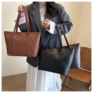 Close-up of three leather tote bags in brown, black, and coffee with gold foil stamping