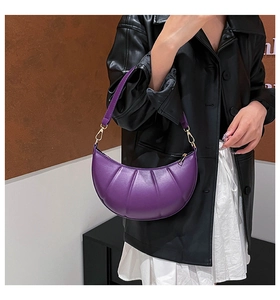 Detail of purple crescent shoulder bag featuring ruched PU leather and gold hardware accents
