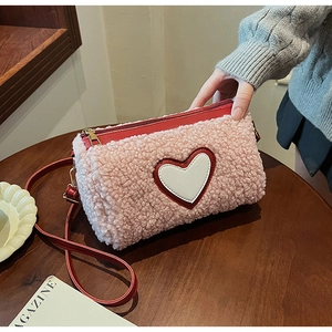 Détail d'un sac à bandoulière en laine rose avec patch cœur blanc et sangle en cuir rouge
