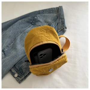 Détails internes d'un sac bandoulière en nylon jaune montrant l'espace pour un mobile