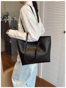 Detalle de bolso tote de cuero negro con letras doradas en un interior minimalista