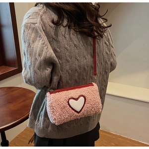 Détail du sac à bandoulière en laine d'agneau rose avec patch cœur et fine lanière rouge