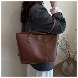 Detail of a brown vintage leather tote bag showing gold lettering and strap variety