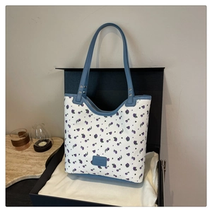Détail du sac cabas en toile à fleurs mauves avec des bretelles en cuir bleu