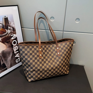 Retro brown oversized tote bag with vintage monogram pattern on a dark wood table
