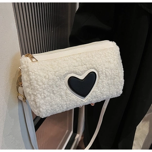 Détail du sac cylindre en fausse fourrure blanche avec patch cœur noir et finitions dorées