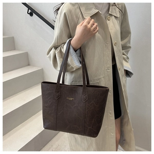 Close-up of brown leather tote bag featuring marble texture and gold lettering logo
