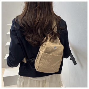 Detailed back view of a beige nylon crossbody chest bag with adjustable black strap