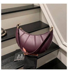 Detail of purple crescent shoulder bag with quilted texture and gold metal hardware