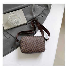 Detail of a brown geometric triangle pattern crossbody bag on a grey blazer background