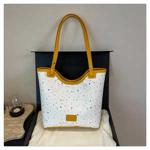 Détail du sac cabas floral avec éclaboussures colorées et poignées en cuir jaune