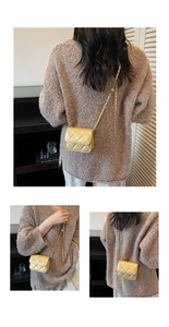 Detail of gold quilted crossbody bag with metal chain strap and luxury stitching