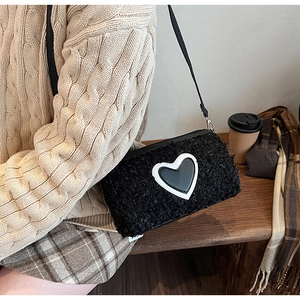 Détail d'un sac bandoulière noir en peluche montrant la texture laine et un patch en cœur