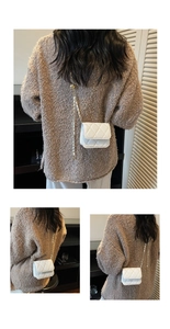 Detail of white quilted mini crossbody bag with gold chain strap on a knit sweater