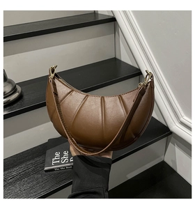 Close-up of brown crescent bag showing vertical pleated texture and golden hardware buckle