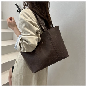 Detail of a deep brown faux leather tote bag with vintage texture and thin shoulder straps