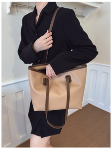 Detalle de bolso tote de cuero beige con ribete marrón y logo New York en letras de oro