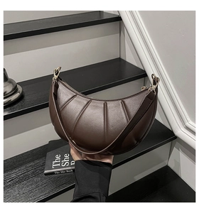 Detail of dark brown pleated crescent bag with gold ring buckle and textured PU leather
