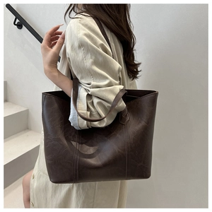 Macro side view of a large brown leather tote bag with vintage texture on a model