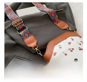 Detail showing cherry print white leather bag with woven strap and gold hardware