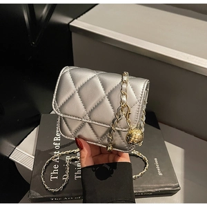 Detail of silver quilted mini bag featuring metallic finish and gold ball chain strap