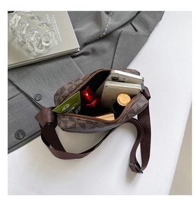 Detail view of brown checkered square bag with daily essentials on a grey blazer background