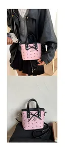 Detail of pink bow handbag with heart pendant and contrast black handle features
